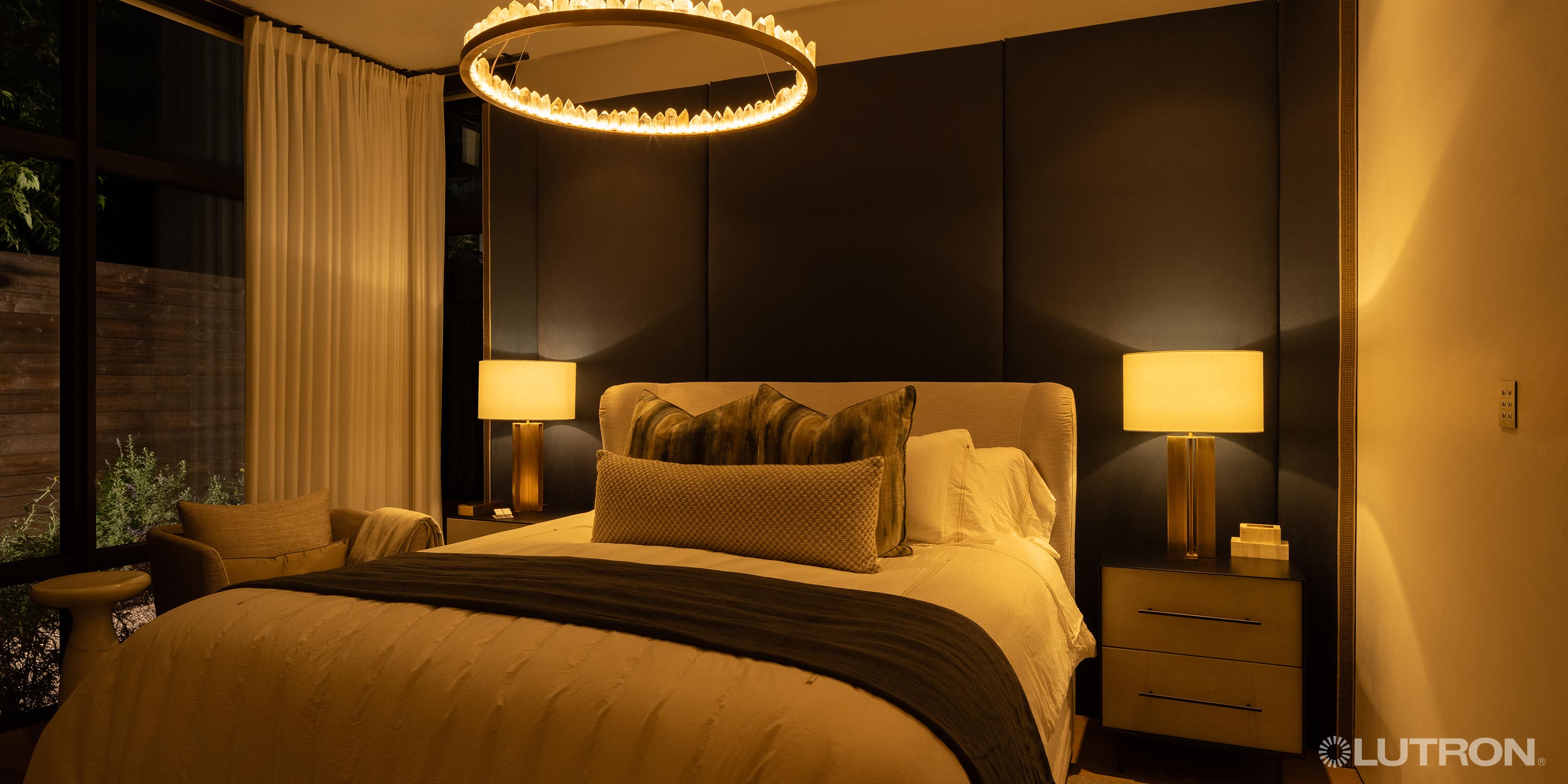 Warmly lit bedroom with elegant lighting, dark accent wall, and plush bedding
