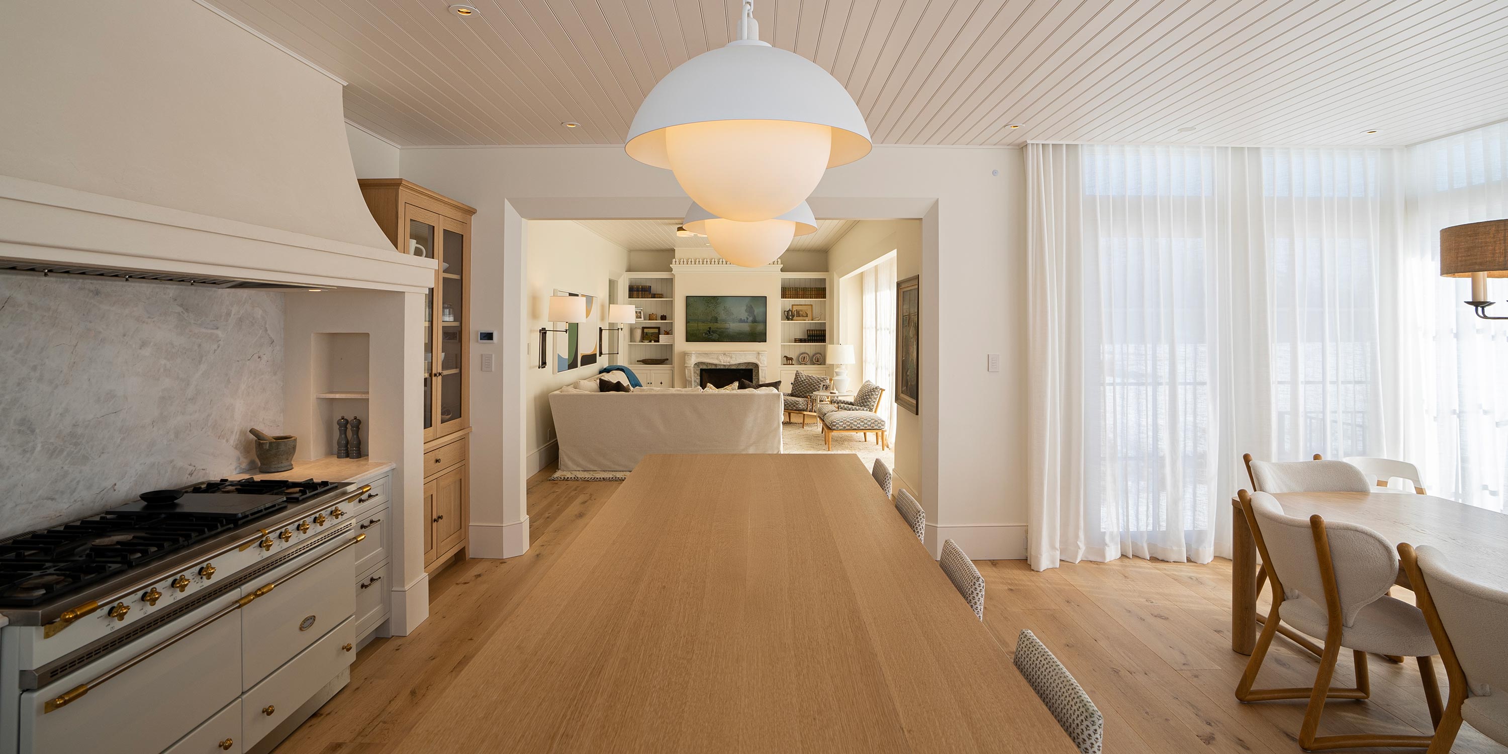 Bright open kitchen and dining space with light wood tones and modern lighting