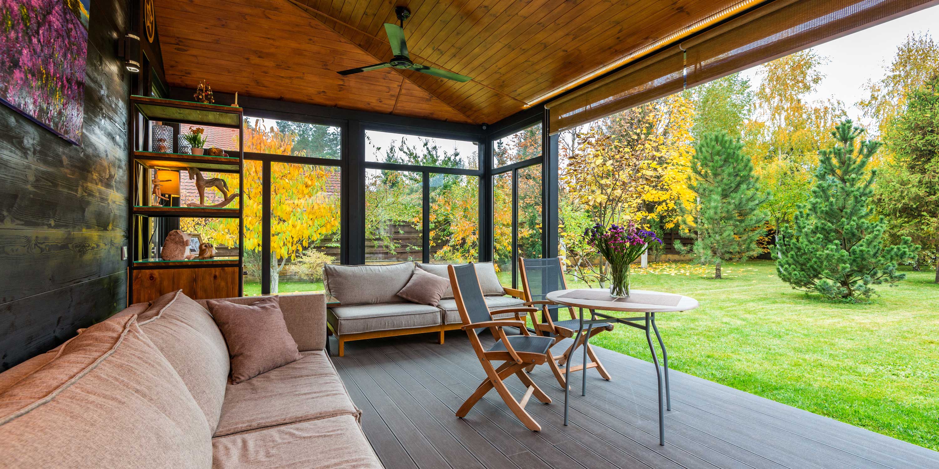 Cozy enclosed patio with cushioned seating, wood ceiling, and garden view